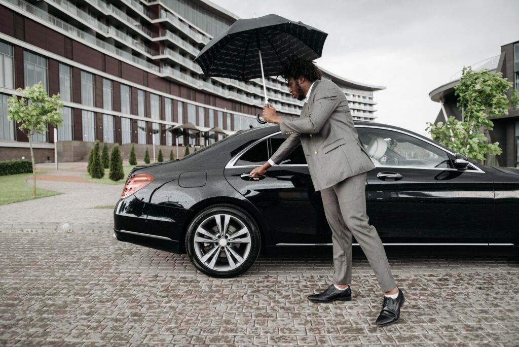 Chauffeur opening a car door while holding an umbrella, Highland Park car service